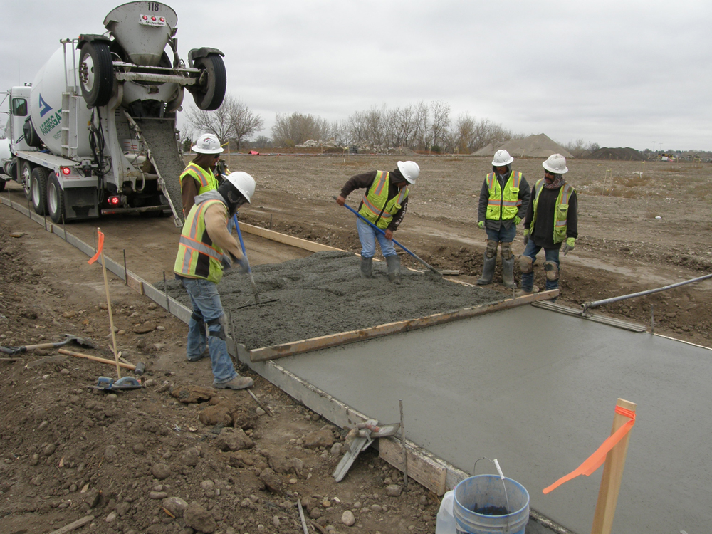 workers spreading concrete for trail