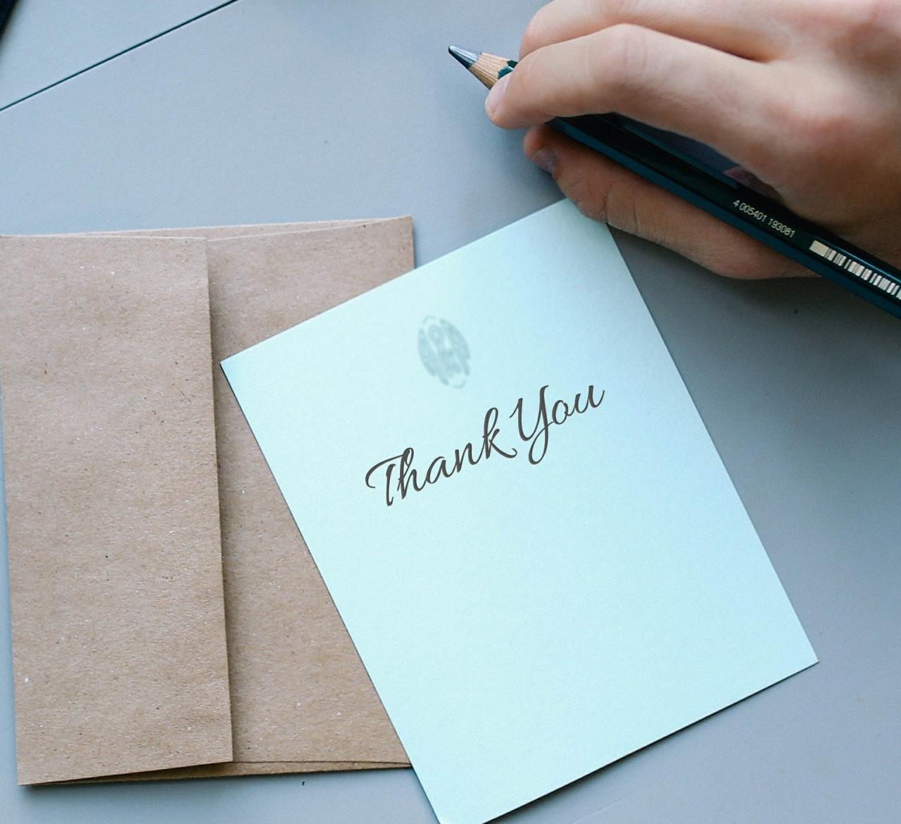 Thank You on Card with Envelope and Hand Holding Pen