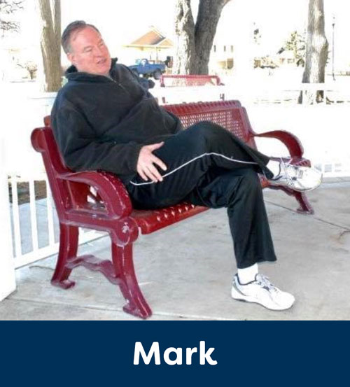 Mark relaxing outside on a red bench