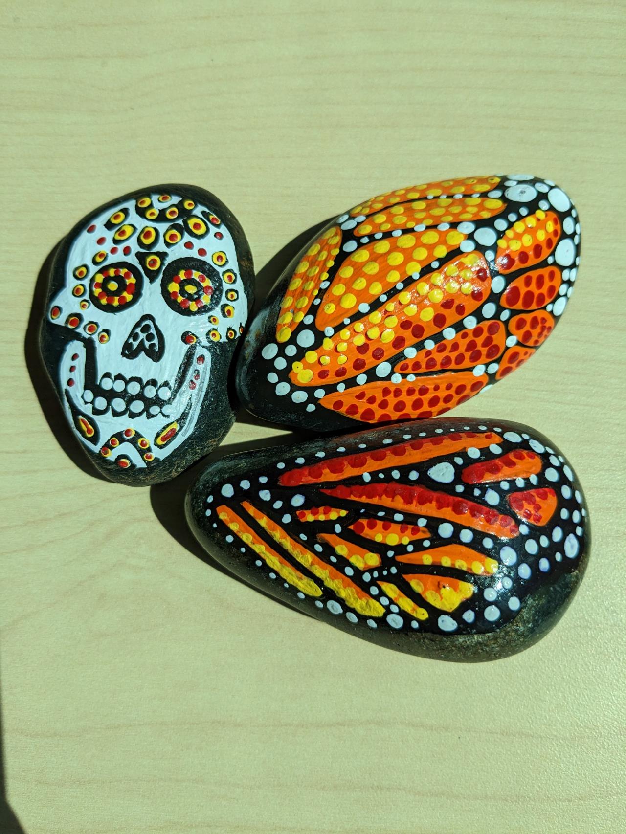 Paintings of butterflies and a skull on rocks