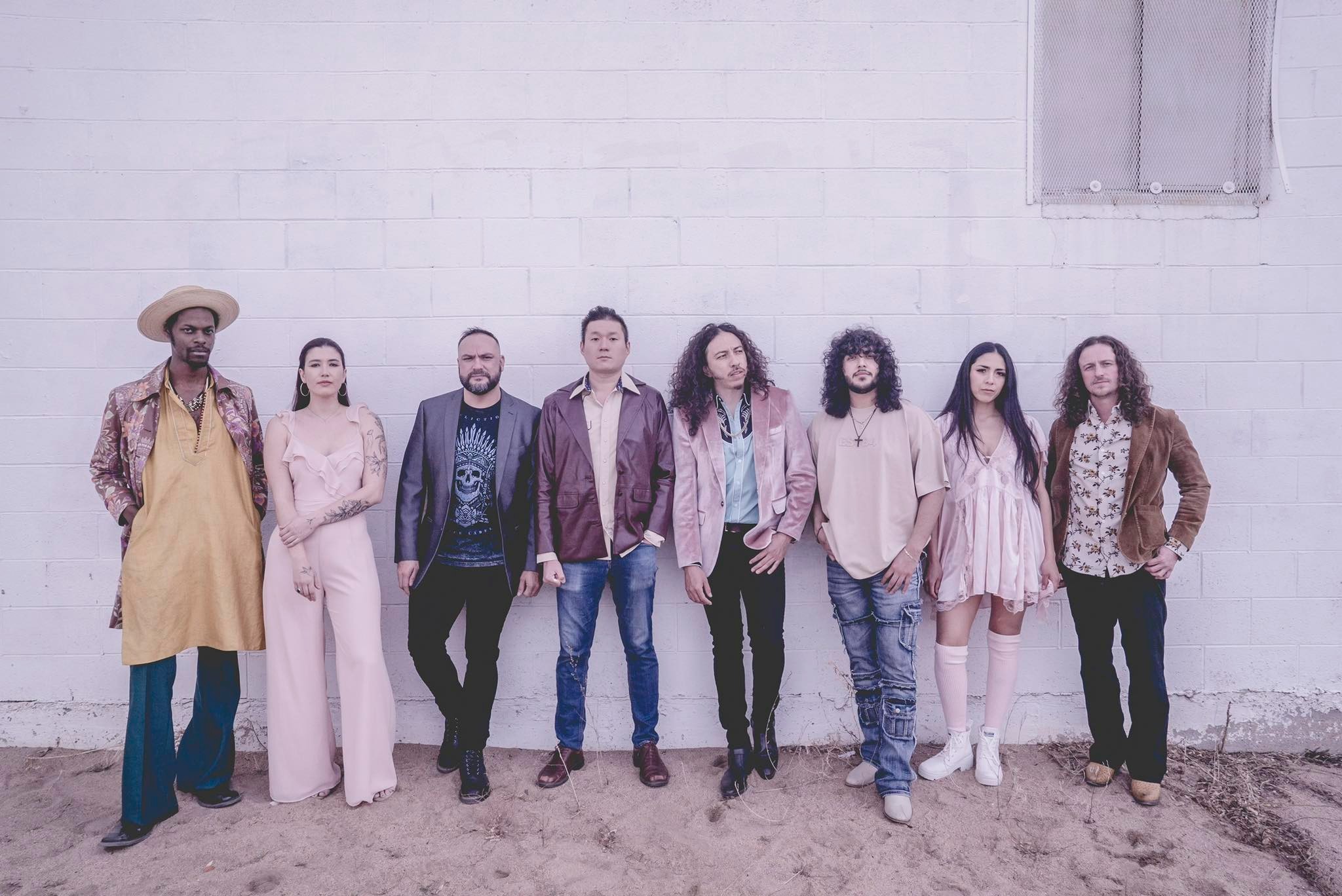 A group of musicians standing against a wall