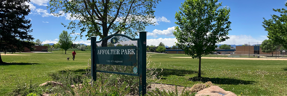 The Affolter Park sign sits in a field of green grass, surrounded by trees.