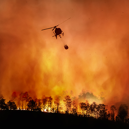 A helicopter drops water on a wild fire