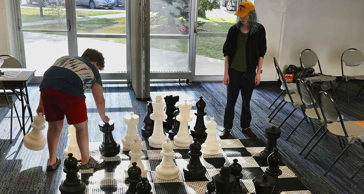 Two people play chess on a life-sized board inside the Longmont Library