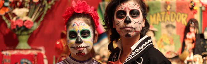 Two young people wear skull makeup in a day of the dead celebration