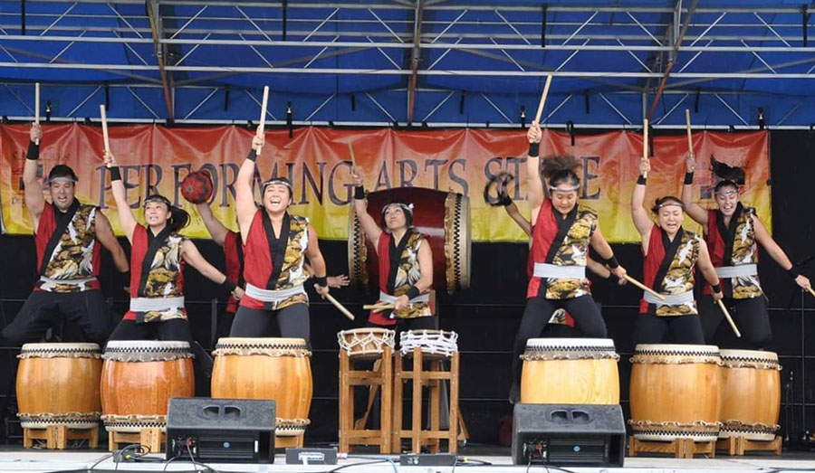 drummers in Japanese dress about to strike large taiko drums