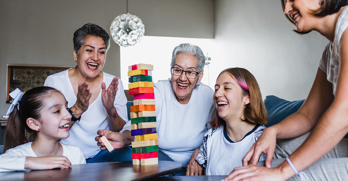 Hispanic family playing Jenga game with grandmother and daughter