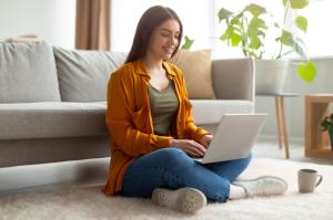 Happy woman sitting on floor with laptop