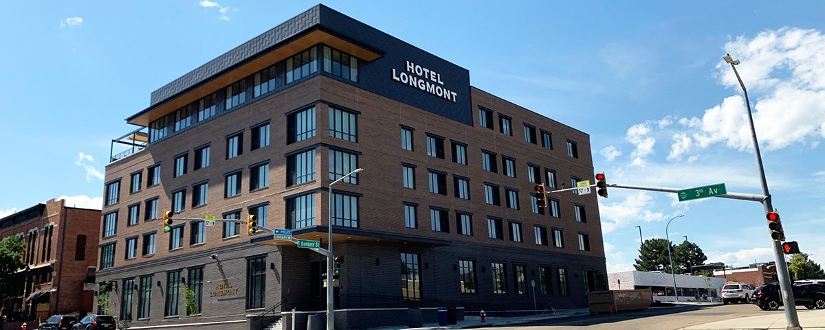 The Hotel Longmont, a brown and black five story building, is viewed from the southeast corner of Kimbark and 3rd.