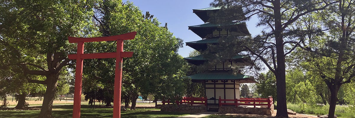 Kanemoto Neighborhood Park is pictured with the Tower of Compassion surrounded by leafy trees.