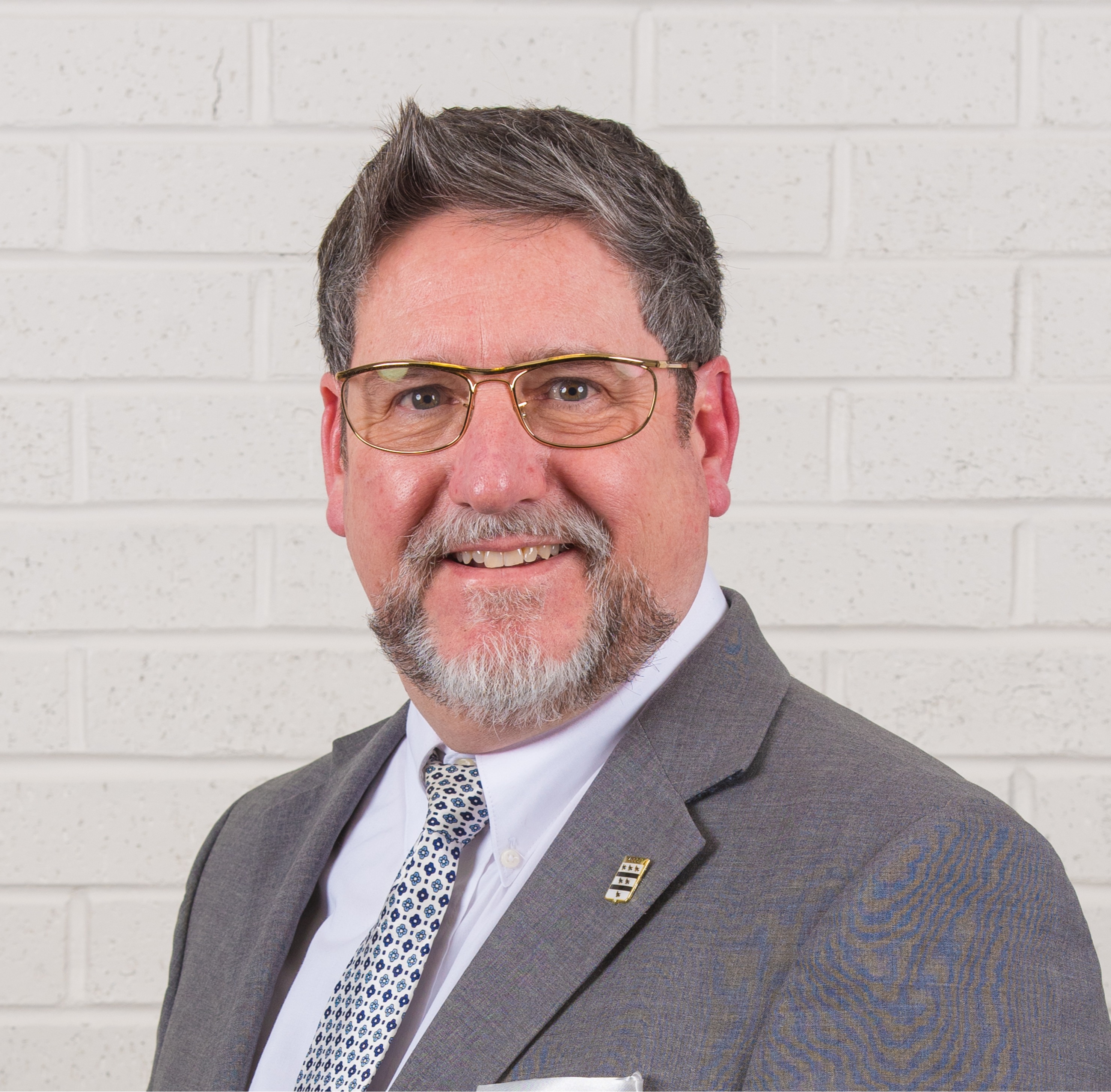 Longmont City Council member Sean McCoy poses for a portrait wearing a white button down, gray suit jacket and patterned red tie