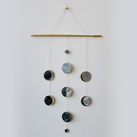 Stages of the moon made with polymer clay displayed in a wall hanging