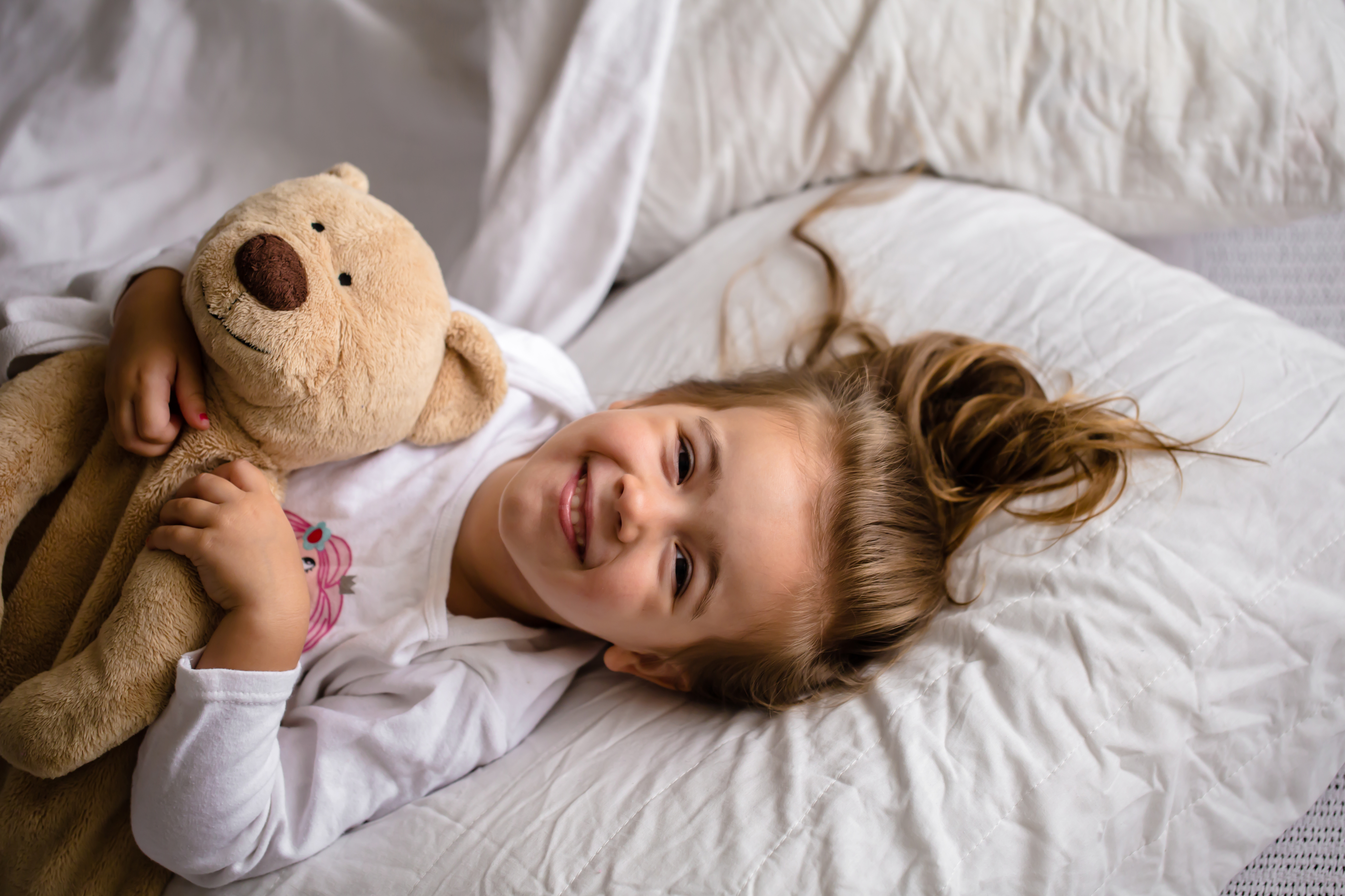 little girl in bed with soft toy the emotions of a child, white bed