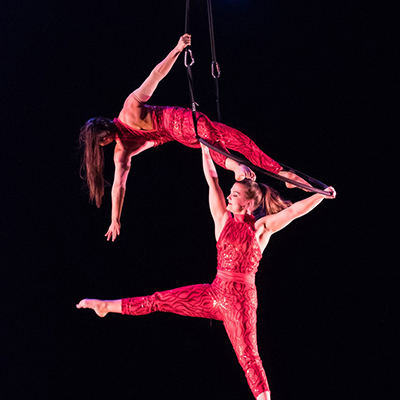 Two aerial dancers suspend from ropes and each other