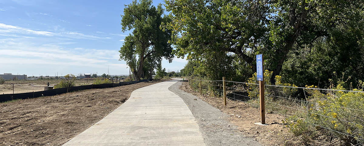 A bike path is pictured next to a wooded area on the Spring Gulch 2 Greenway