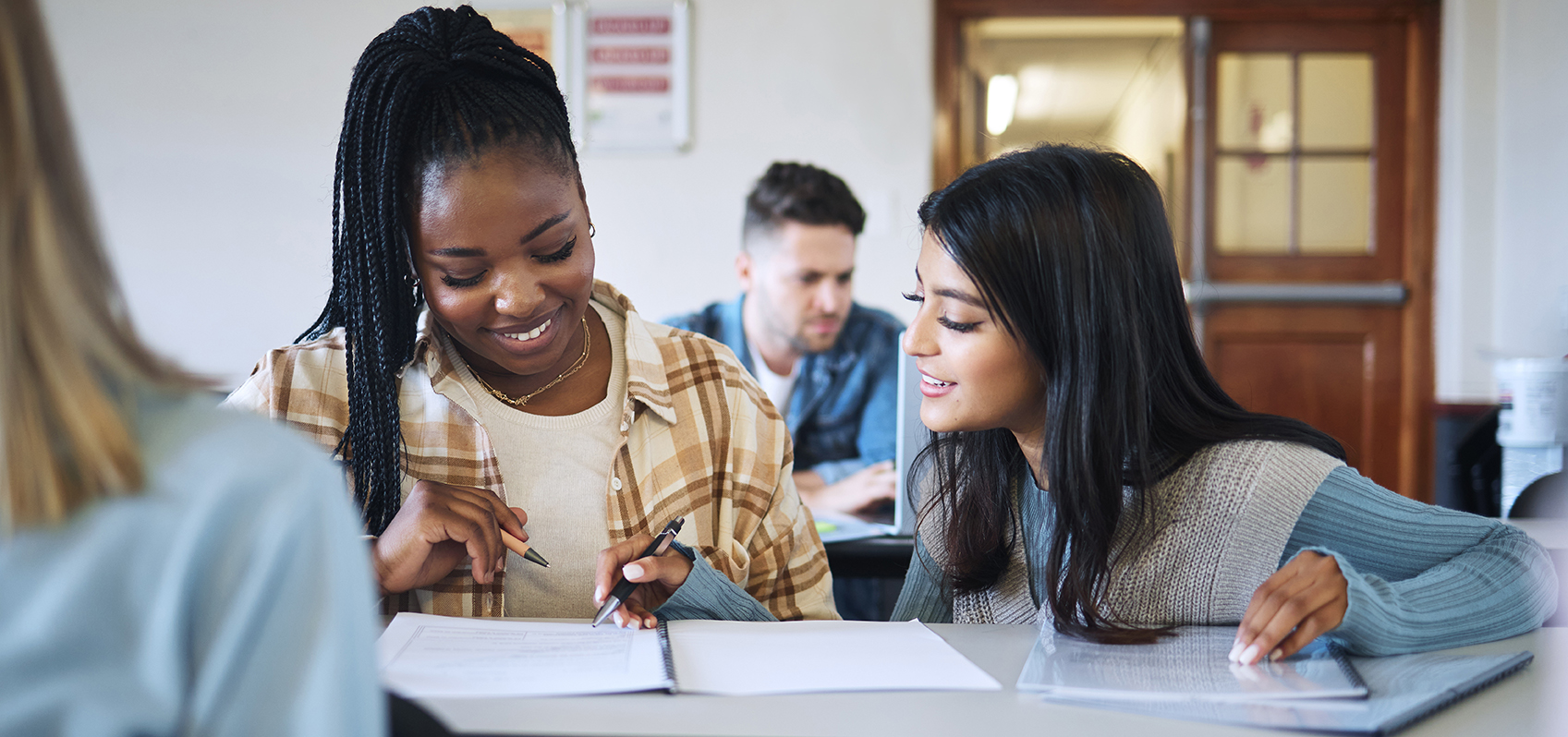 Education, teamwork or students in classroom for working together on university, college or school research project. Diversity, smile or happy friends learning, knowledge study or writing in notebook.