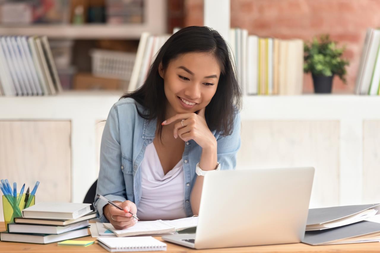 Woman smiling while taking notes at computer