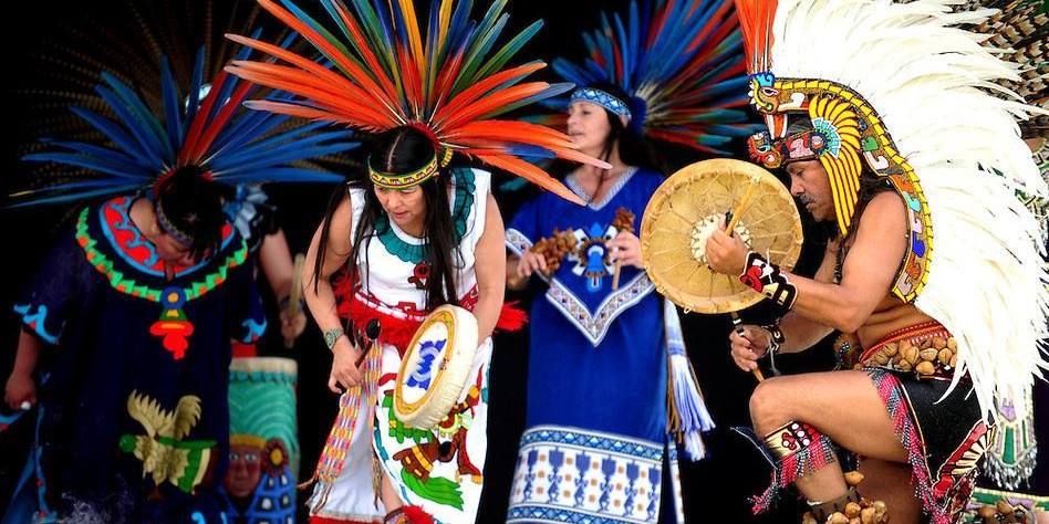 Indigenous people are dancing in colorful traditional attire.