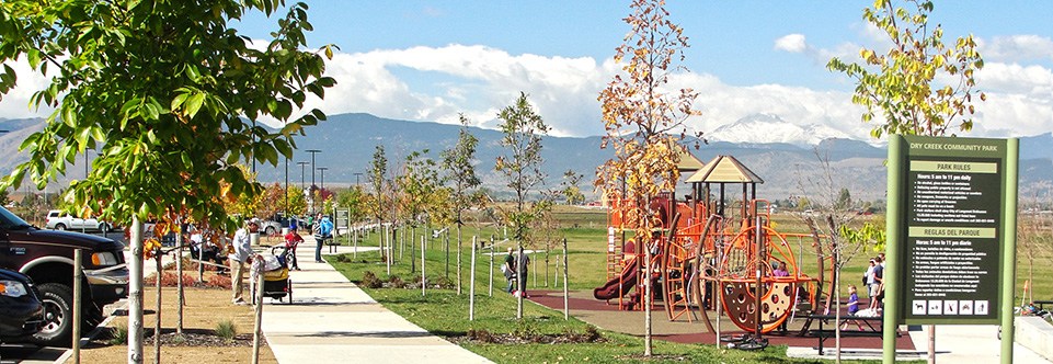 A playground area at Dry Creek Park is pictured with the front range mountains in the background.