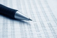 Columns of numbers on white paper with black pen sitting atop