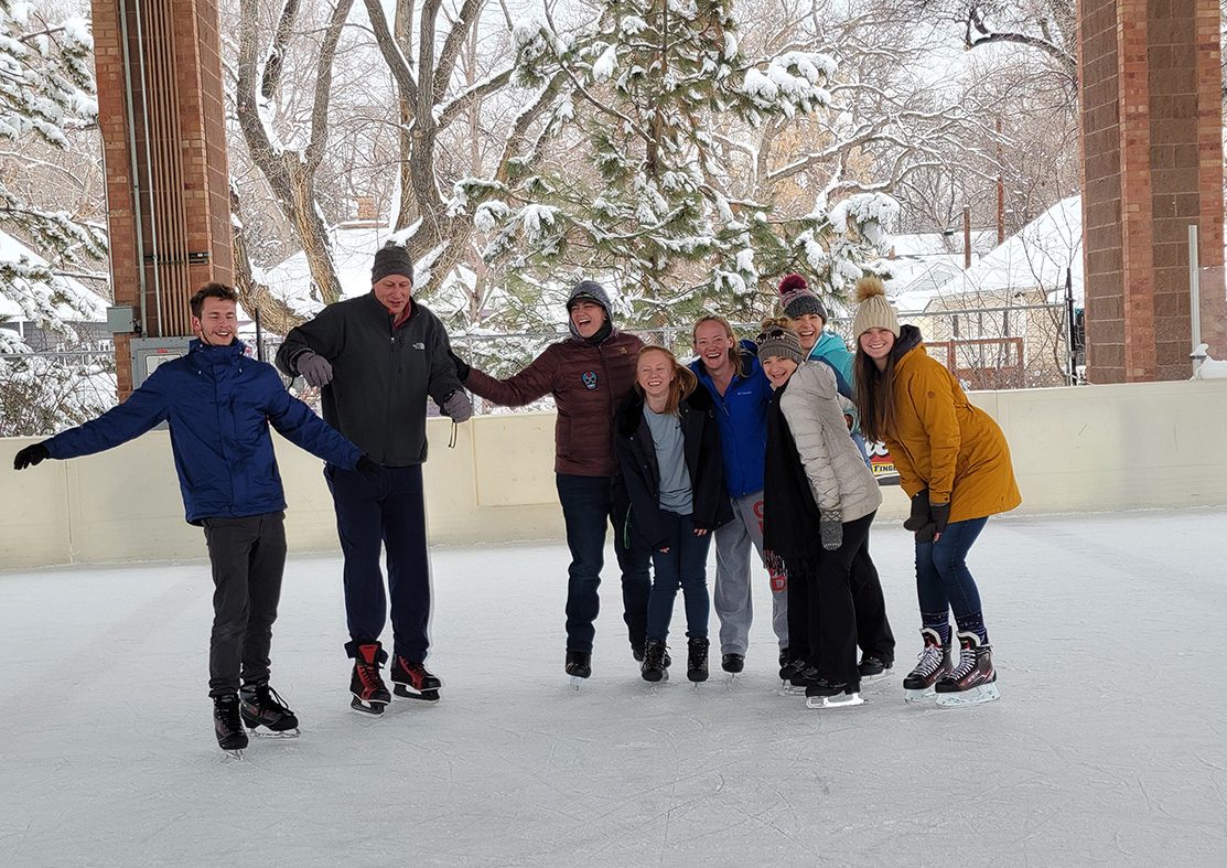 Group of adults on ice skates smiling while posing for photo