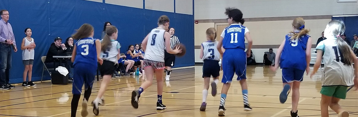 Girls running down the basketball court during a game.