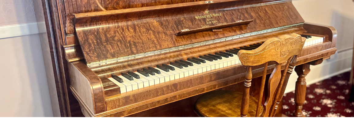 Steinway & Sons antique piano with chair next to it