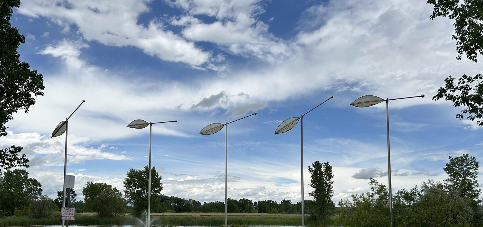 five abstract sculptures on tall poles that look like feathers