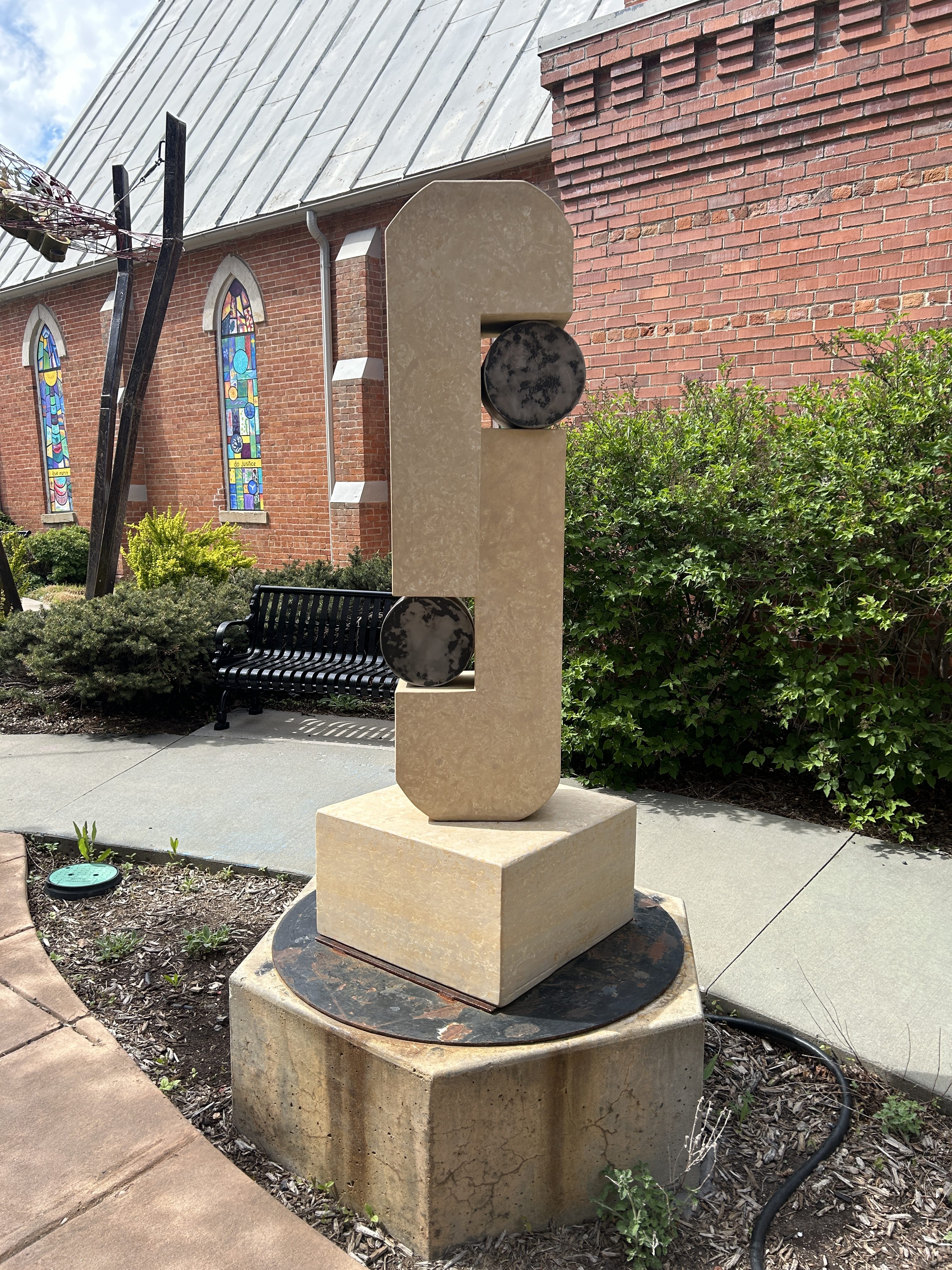 an abstract stone and steel sculpture in front of a church