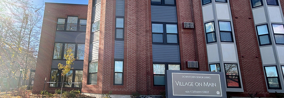 This exterior view of the Village on Main apartments includes a sign that reads, "Downtown Senior Living, Village on Main, 600 Coffman Street."