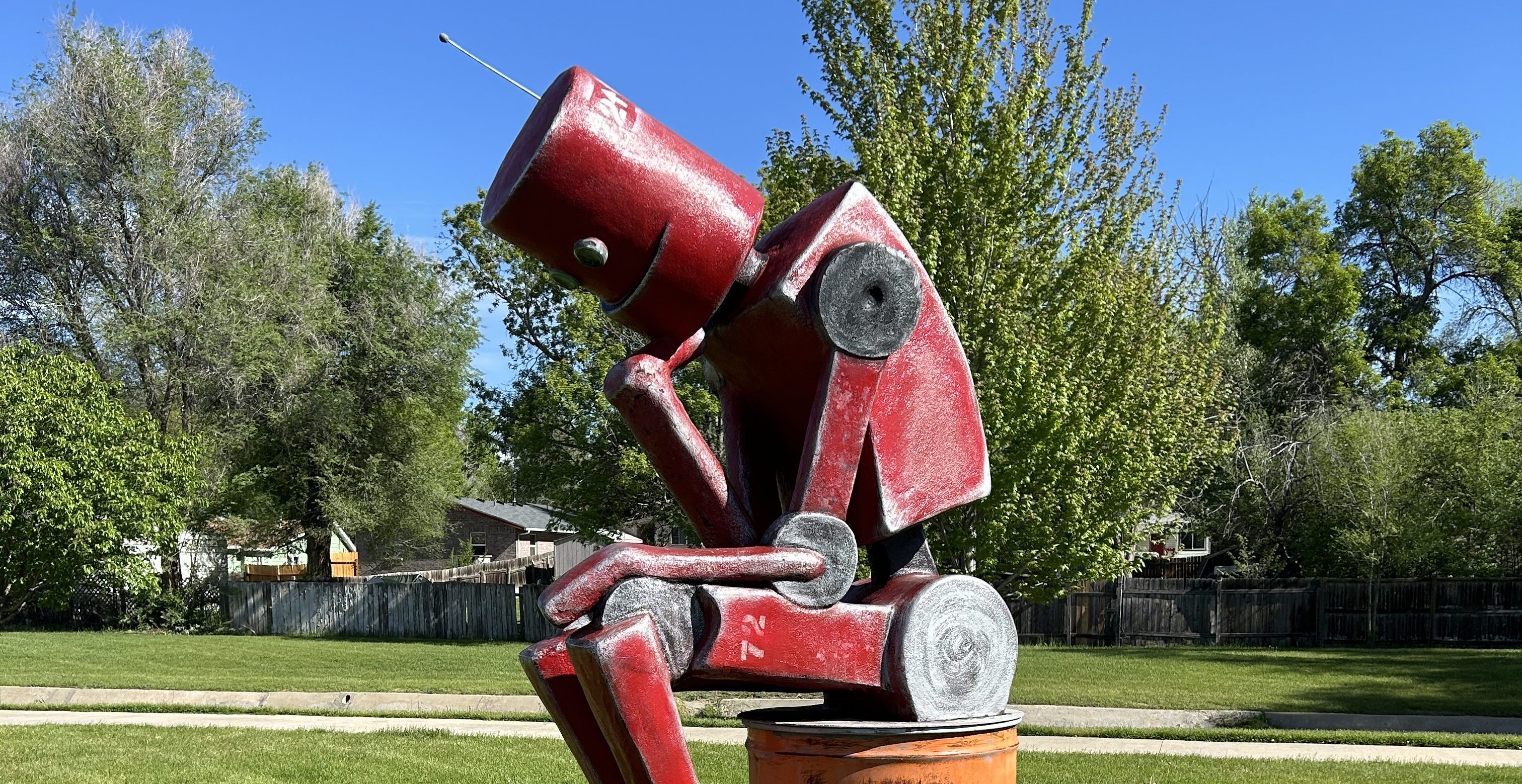 a close up of a red pensive robot in a park