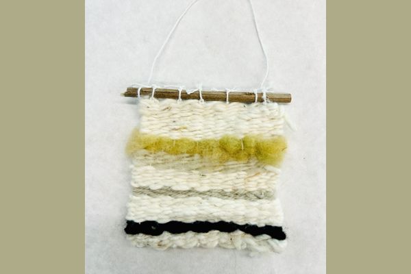 Woven wall hanging in cream, yellow, and black yarn