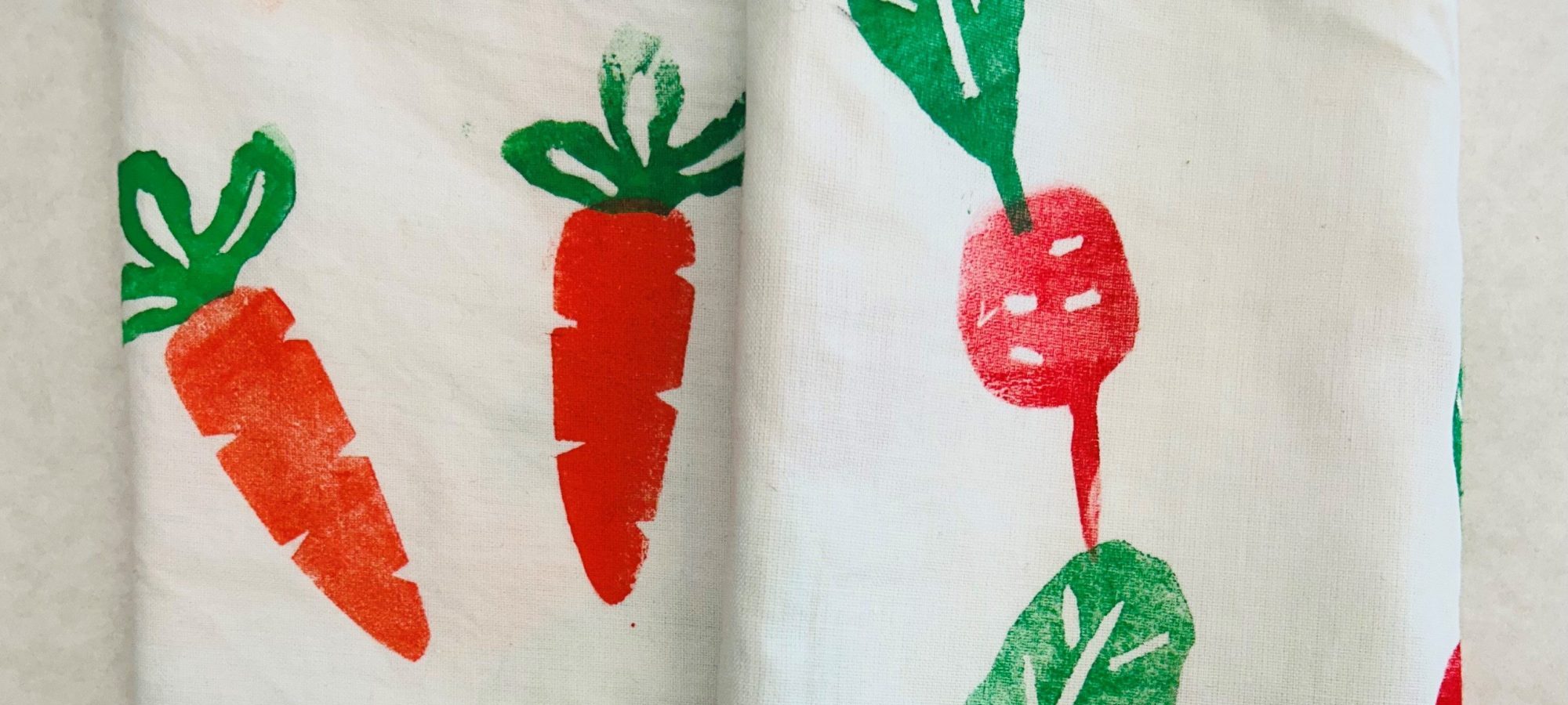 Red and green radish print on white cloth and orange and green carrot print on white cloth