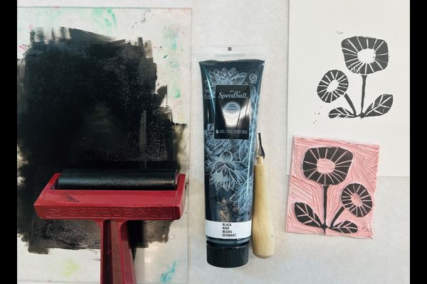 Block printing, with ink, roller, and two examples of prints on white and pink paper