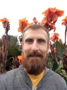 Image of man (poet Eric Baus) among orange flowers 