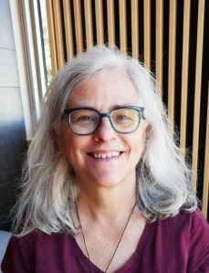 Photo of a woman with grey hair against a wood background