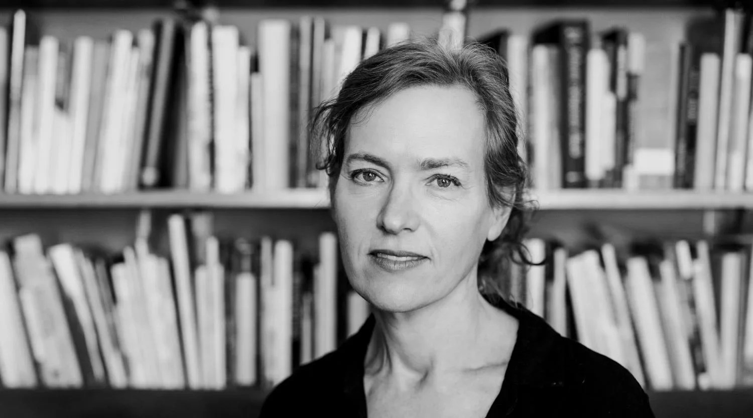 Black and white image of a woman standing in front of a bookshelf