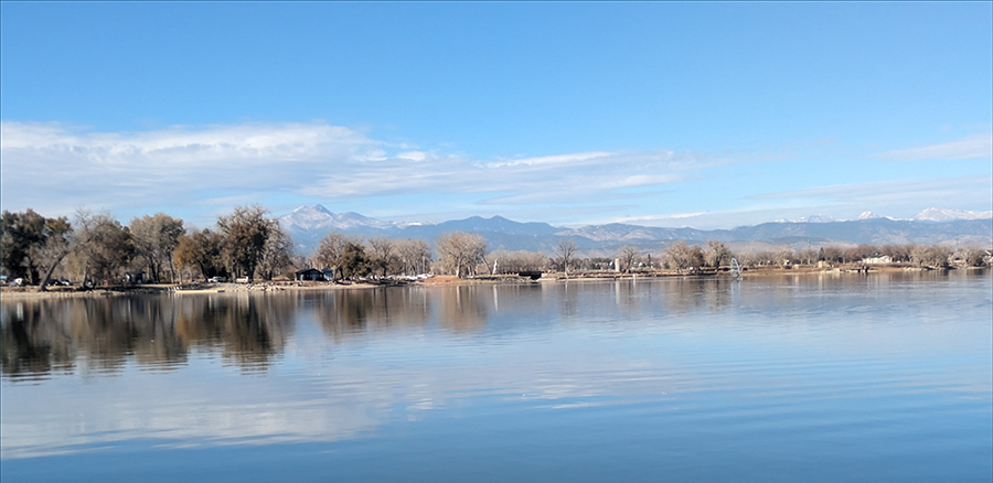 Union Reservoir is seen on a sunny day with snow capped mountains in the background.