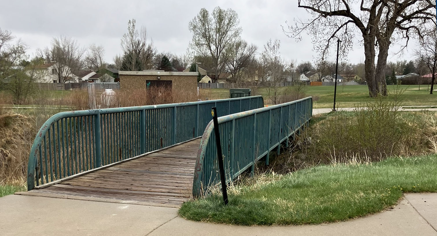 A pedestrian bridge at Garden Acres Park is shown in disrepair prior to replacement in 2025.