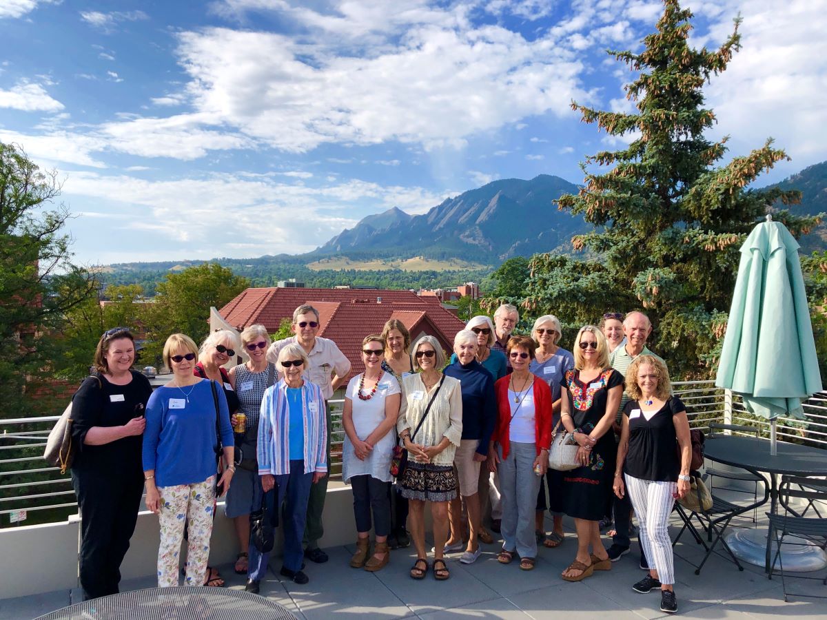 A group of people standing on a rooftop with mountains in the background