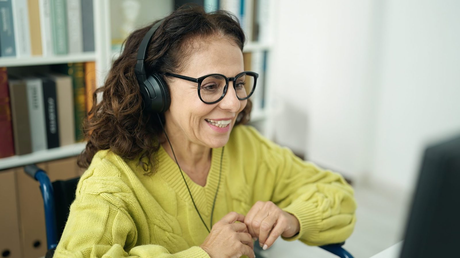 a woman wearing headphones at a computer smiling and doing work