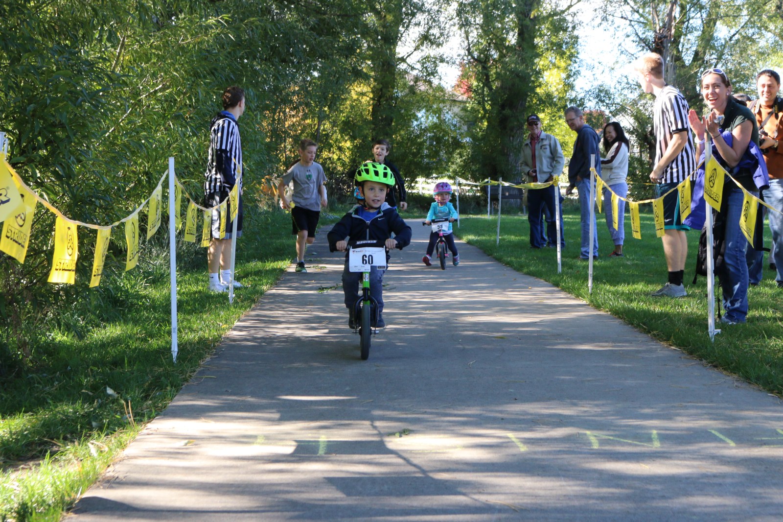 A balance bike rider crosses the finish line at a race