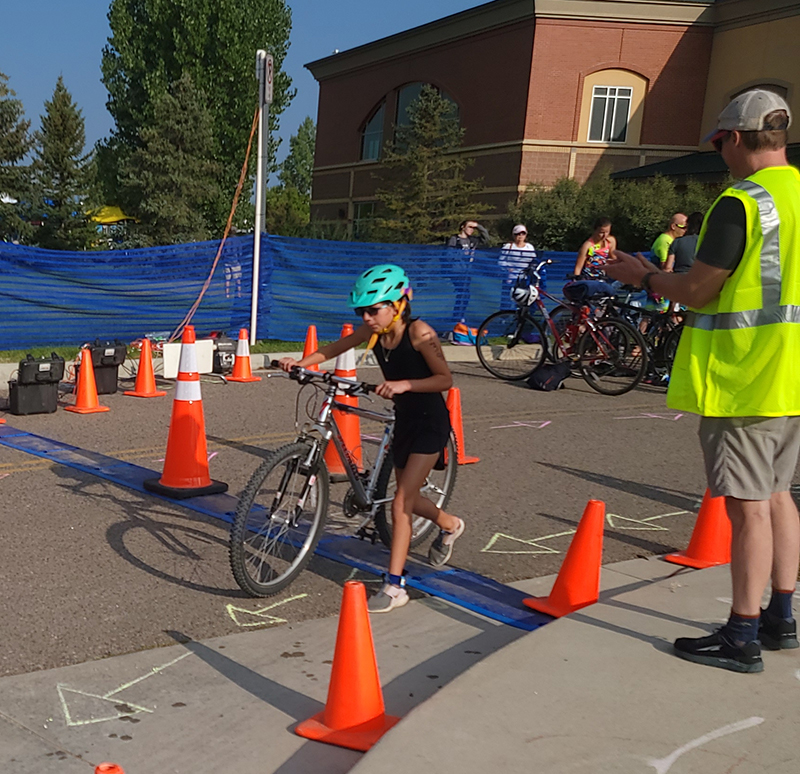 A triathlon participant runs with their bike