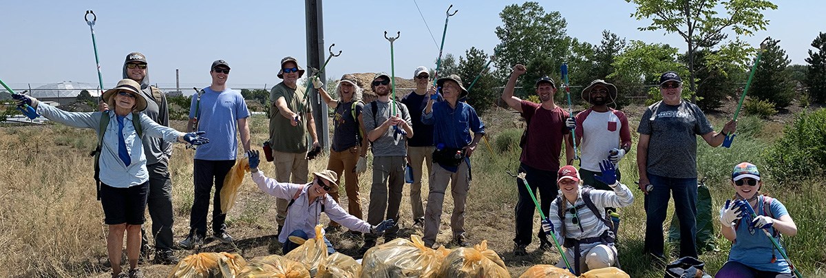 Fourteen participants in the Clean Up Green Up volunteer program post of a photo with bags of trash they've collected.
