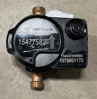 Closeup of a Neptune water meter, with a reading of 15477582.