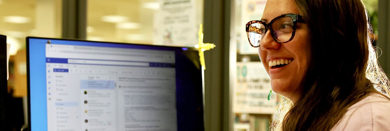 Librarian smiling at the tech desk upstairs at the Longmont Library