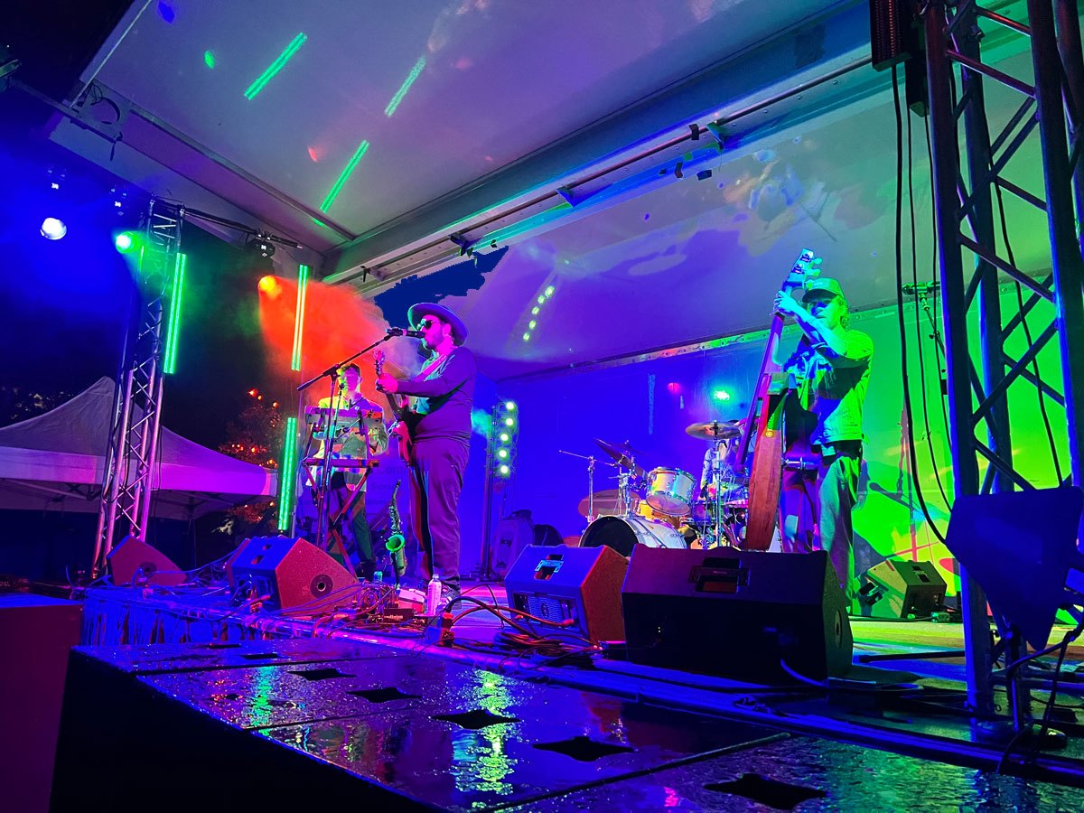 Band performing on stage with colorful blue orange and green lights