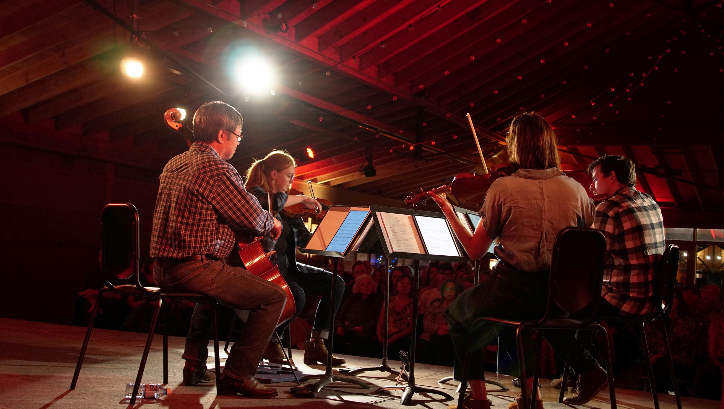 Amber lighted small quartet performance on stage with crown in background