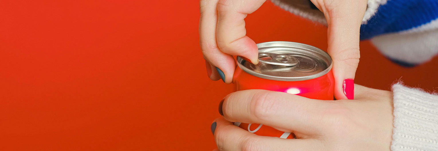 a close up of a hand opening a soda