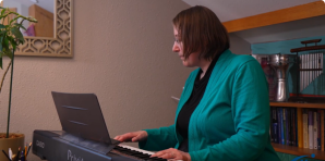 Faith Halverson-Ramos plays an electronic keyboard at Soundwell Music Therapy, facing to the viewer's left. 